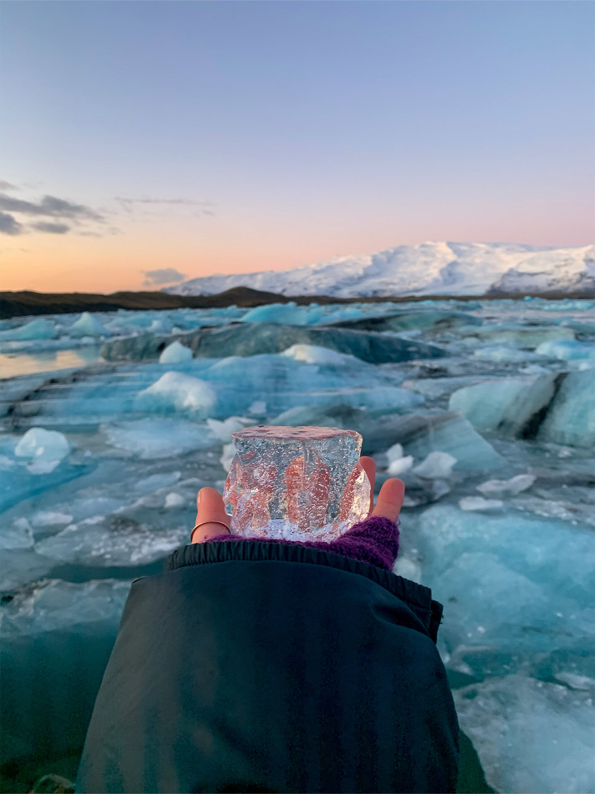 Eisklotz in Hand vor gletscher